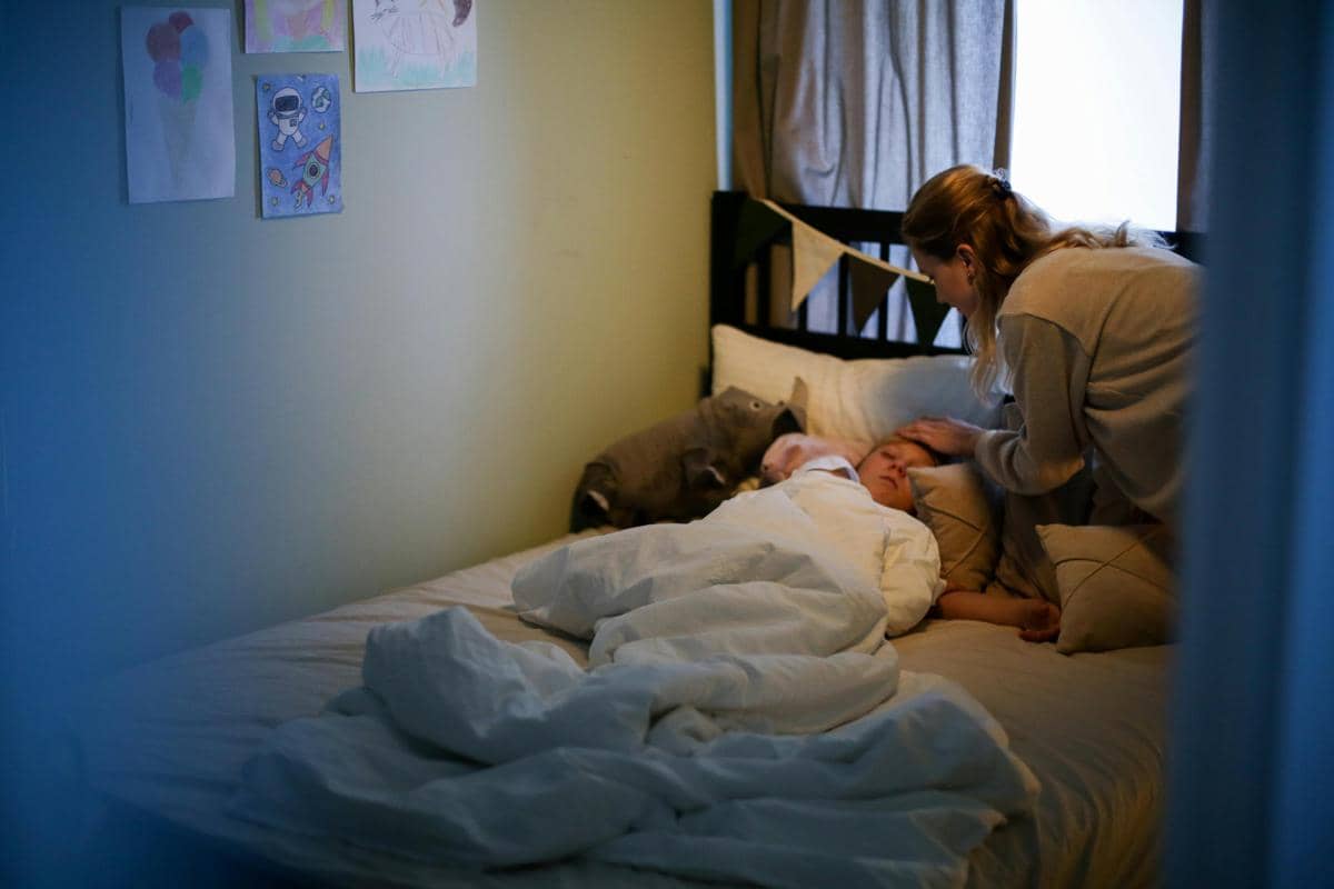 Seorang ibu sedang merawat anaknya yang sedang sakit.