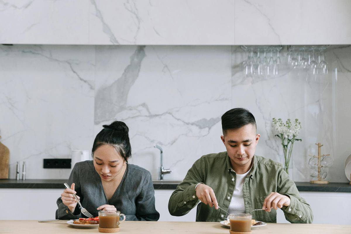 Pasangan suami istri sarapan bersama di meja makan.