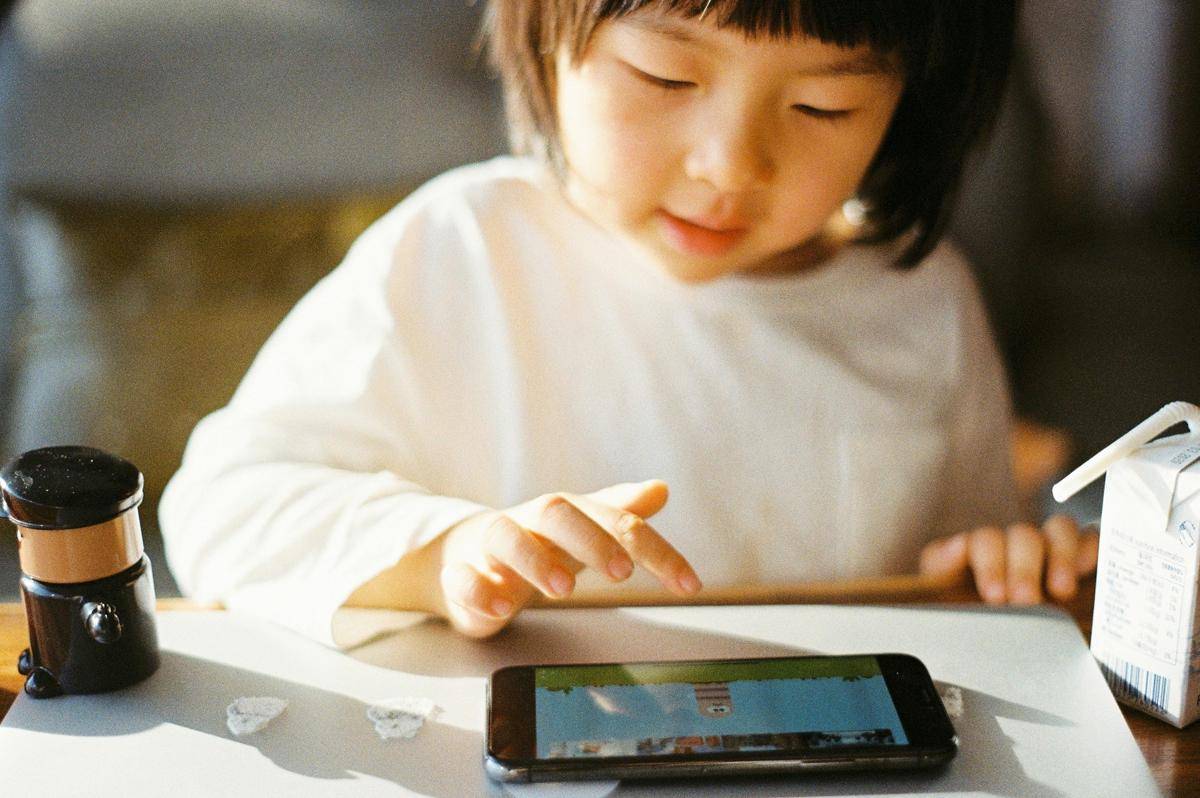 Ilustrasi anak yang sedang bermain ponsel. (unsplash.com/zhenzhong liu)