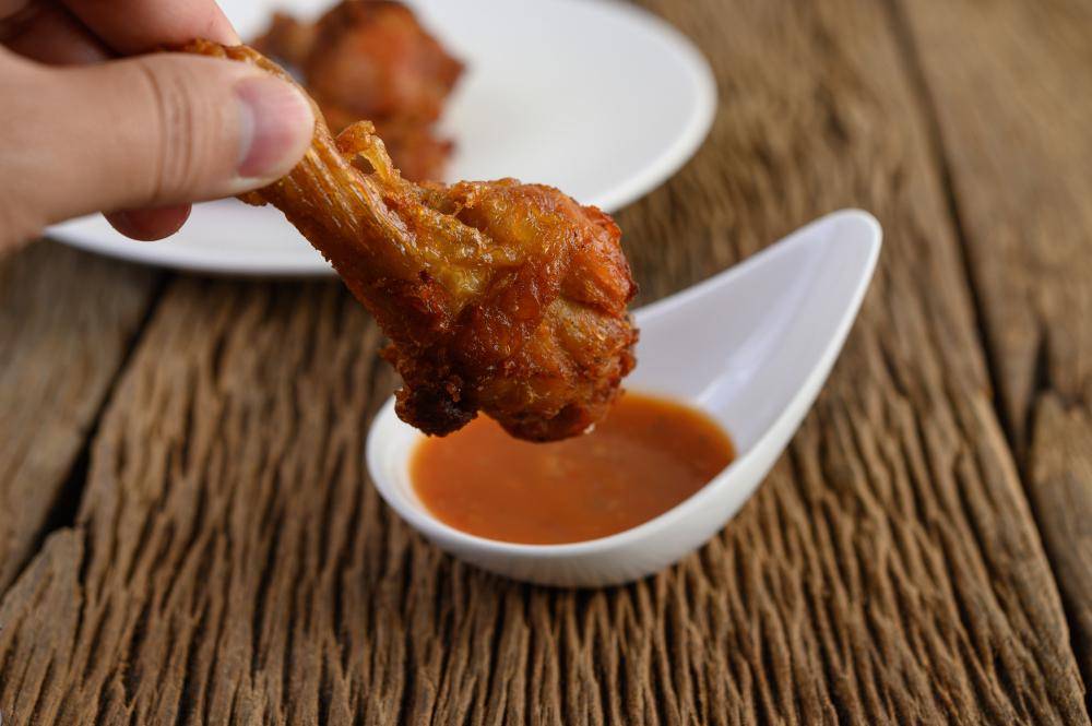 ilustrasi menikmati ayam lolipop dengan saus (freepik.com/jcomp)