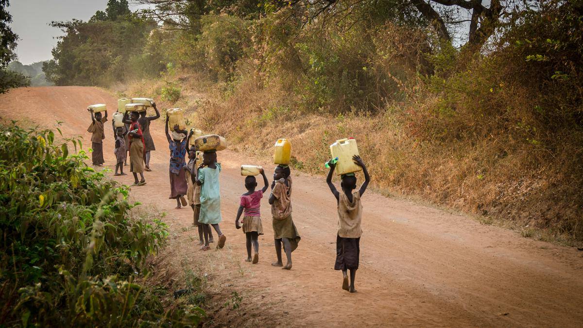 Sekelompok orang di benua Afrika berjalan membawa kontainer (unsplash.com/@ackley5)