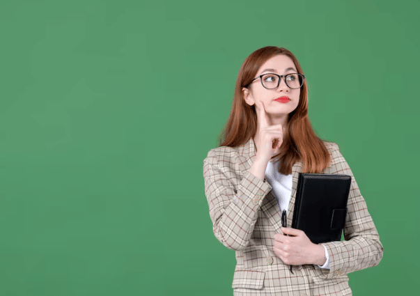 Perempuan berambut panjang mengenakan kacamata dan jas kotak memegang buku hitam sambil berpikir di latar hijau polos.