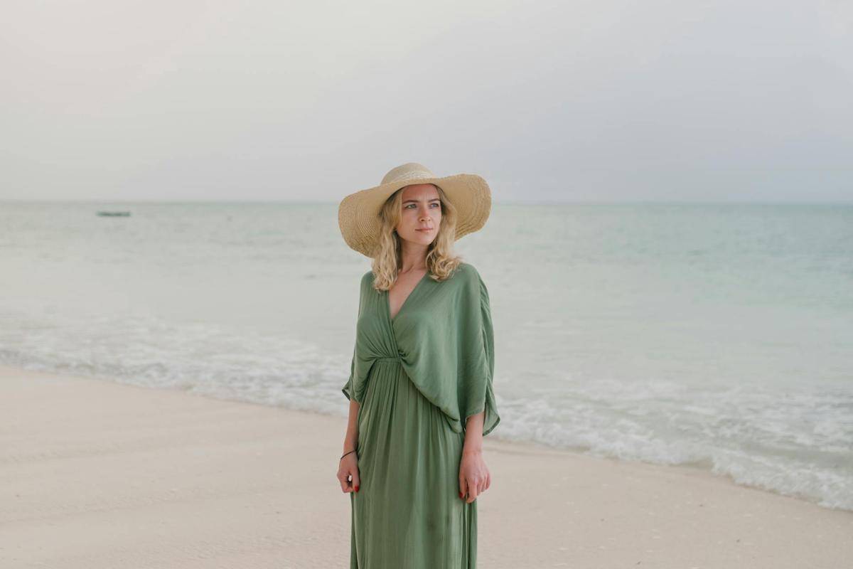 ilustrasi perempuan memakai topi di pantai (pexels.com/Julia Volk)