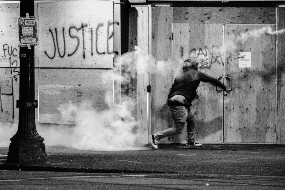 gambar seorang pria berlari menghindari gas air mata (unsplash.com/Tito Texidor III)