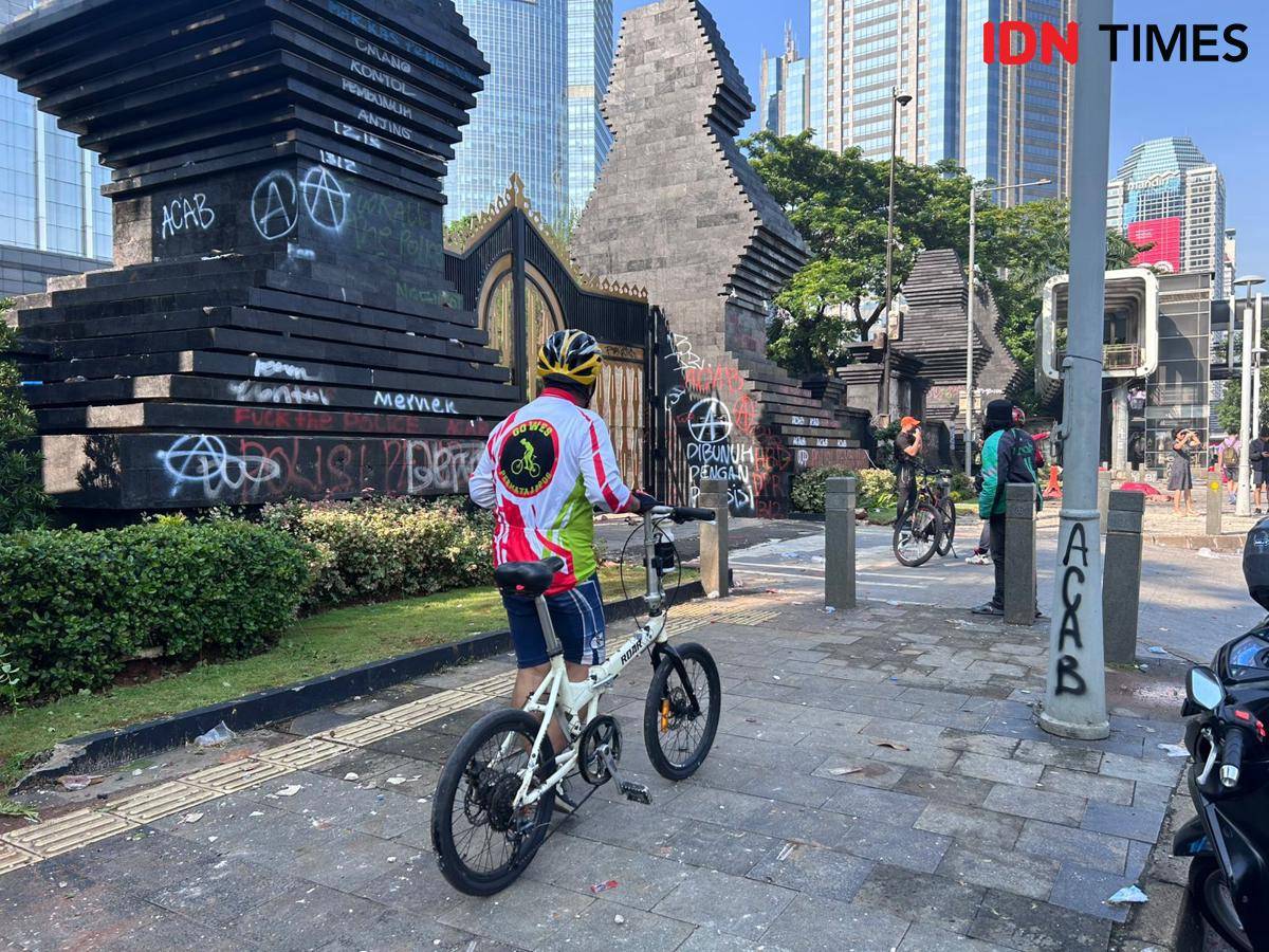 Warga berfoto di depan Gerbang Polda Metro Jaya yang rusak, Sabtu (30/8/2025). (IDN Times/Fadhliansyah)