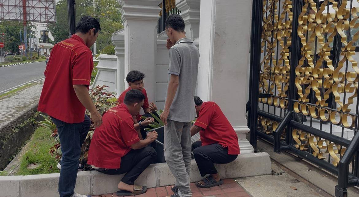 Petugas kebersihan DPRD Sumbar mengumpulkan batu di luar kantor DPRD Sumbar (Foto: IDN Times/Halbert Caniago)