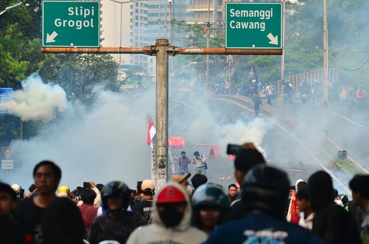Kerumunan demonstran dengan asap mengepul 