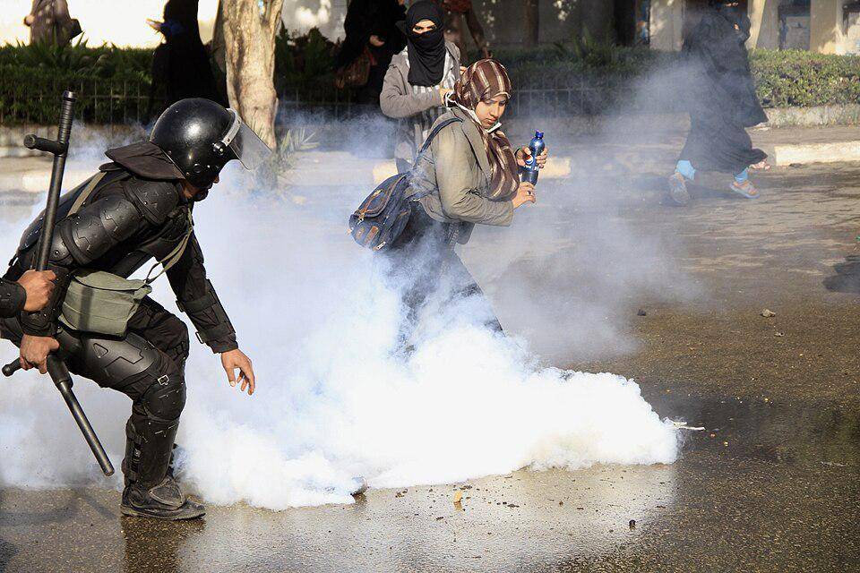 seorang polisi dan wanita menghindari gas air mata (commons.wikimedia.org/Hamada Elrasam)