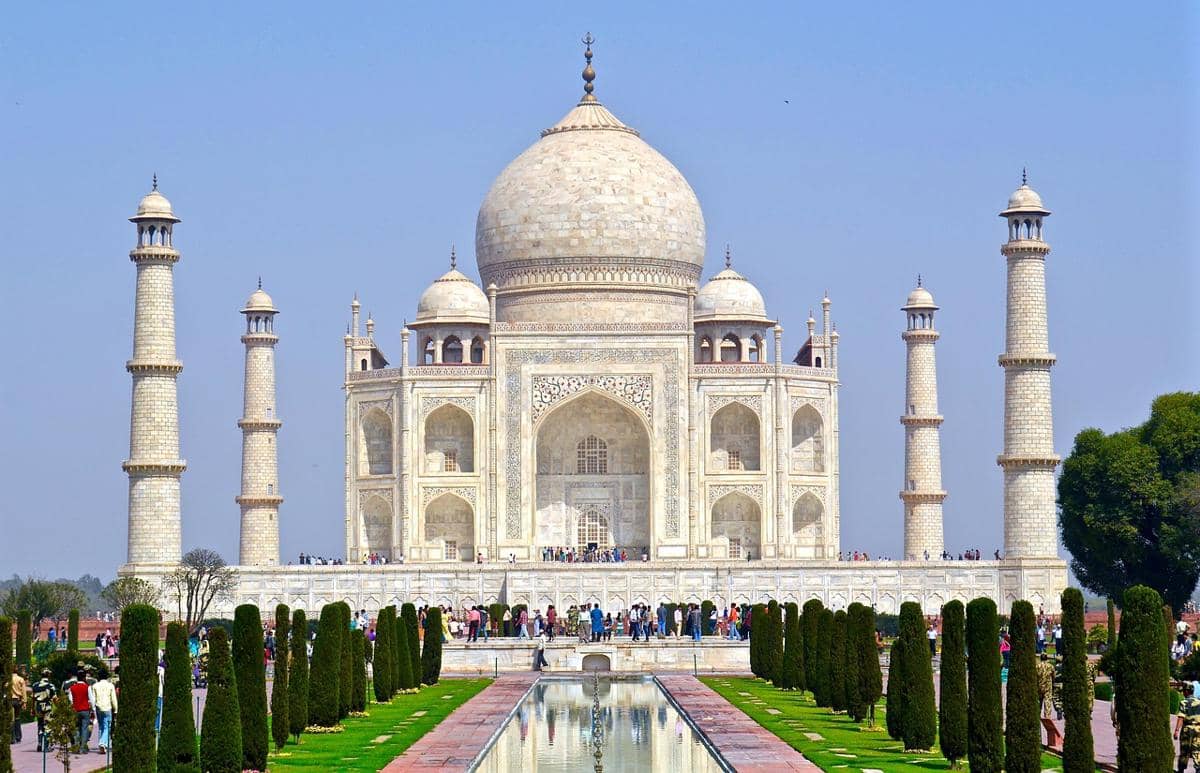 Taj Mahal berarsitektur marmer putih berdiri di Kota Agra dengan kubah utama dan empat menara di bawah langit cerah.
