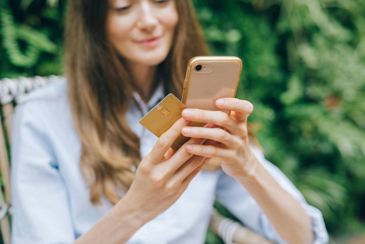 ilustrasi wanita memegang ATM dan handphone