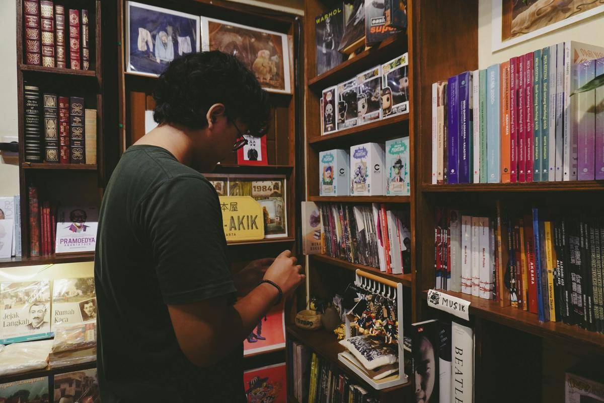 ilustrasi pria dengan rak penuh buku (unsplash.com/Yazid N)