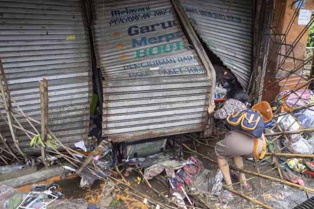 Salah satu ruko terdampak banjir dengan pagar dan garasi rusak, sementara sejumlah barang tampak terseret dan berserakan. (EPA/Made Nagi via sbs.com.au)
