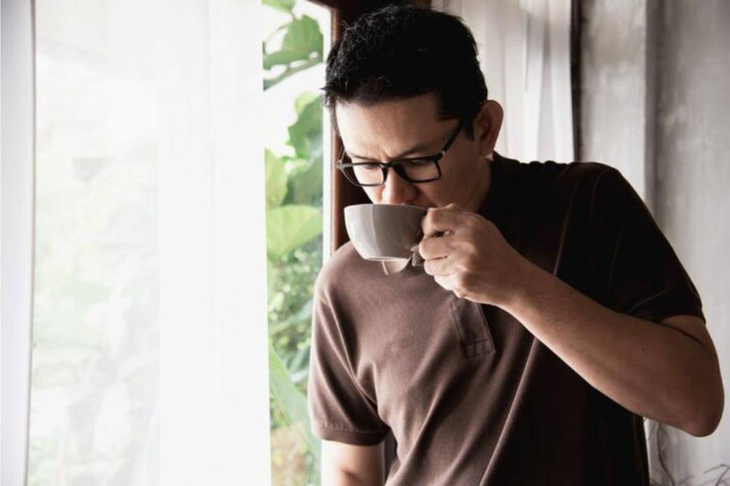 Seorang laki-laki minum secangkir kopi.
