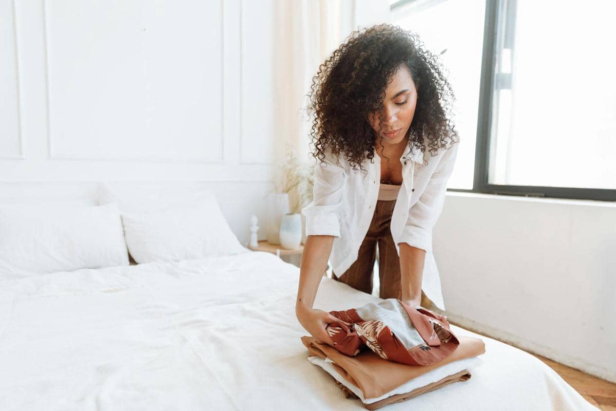 Seorang perempuan sedang merapikan kamar tidur