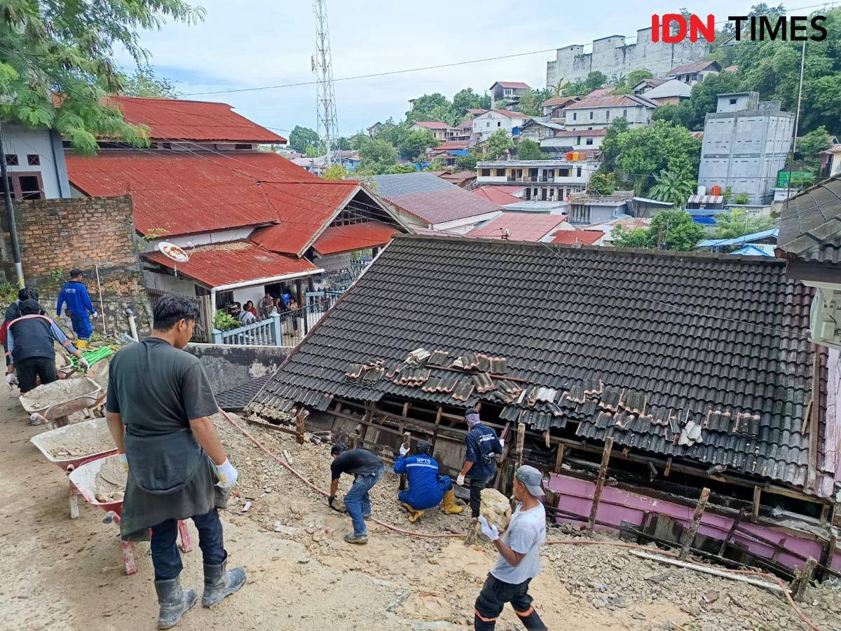 Petugas dari Dinas PU dan BPBD Balikpapan membersihkan material longsor.