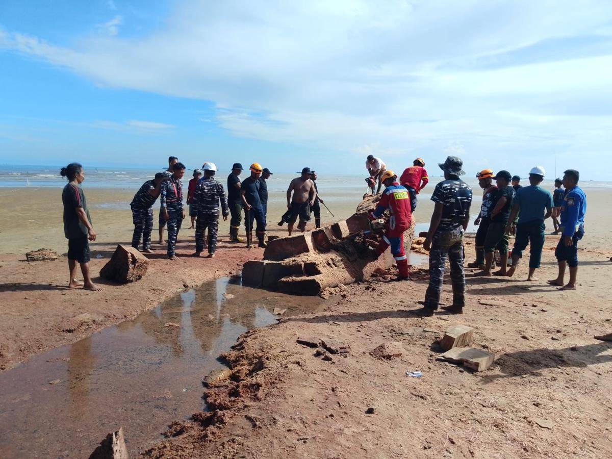 Warga dan petugas gabungan mengangkat kayu yang sudah dipotong.