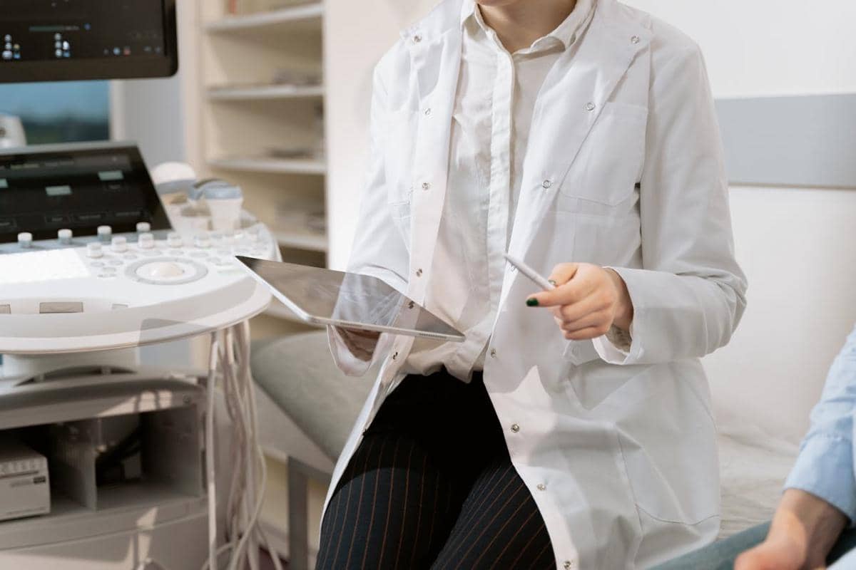 Seorang dokter perempuan berkonsultasi dengan pasien pria di ruang klinik sambil mencatat informasi medis.