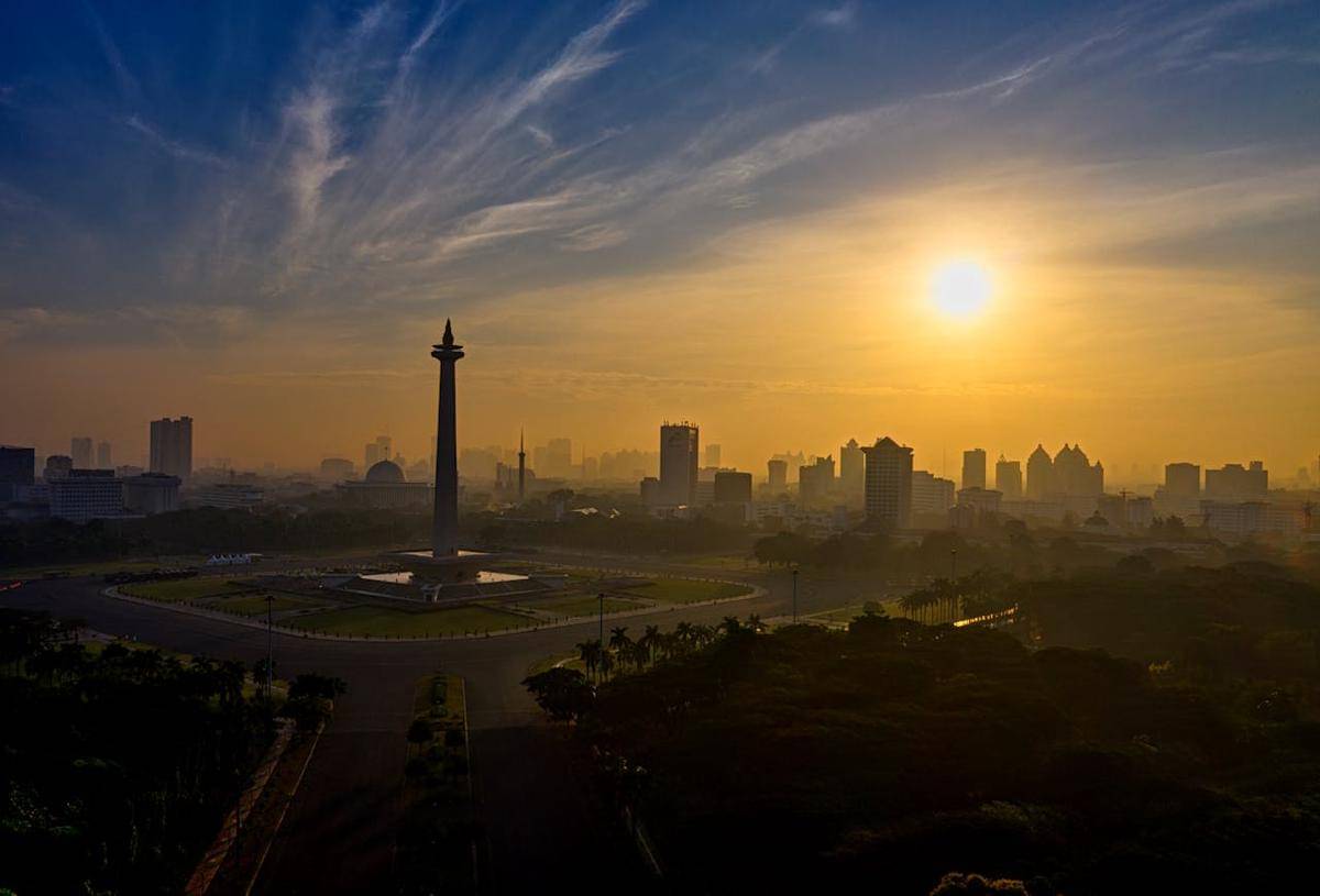Monumen Nasional (Monas) di Jakarta dengan latar belakang langit jingga dan siluet gedung-gedung tinggi (pexels.com/Tom Fisk)