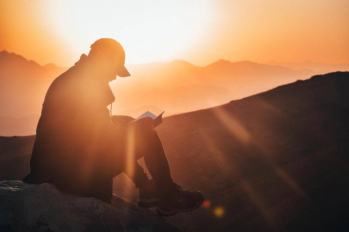ilustrasi pendaki sedang menghabiskan waktu membaca sambil menikmati sunset di gunung (pexels.com/Suliman Sallehi)