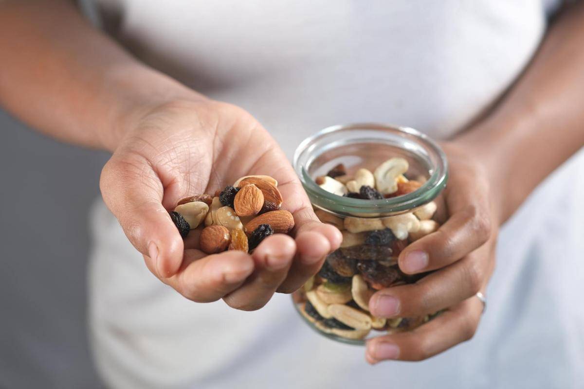 Seseorang mengambil segenggam kacang-kacangan dari toples.