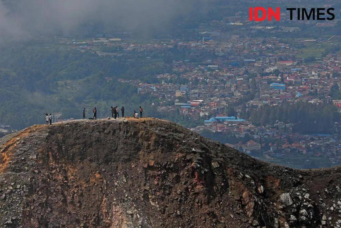 Pendaki menyaksikan pengibaran bendera merah putih raksasa di Puncak Gunung Sibayak, Karo, Sumut dari kejauhan, Sabtu (17/8/2024). (IDN Times/Arifin Al Alamudi)