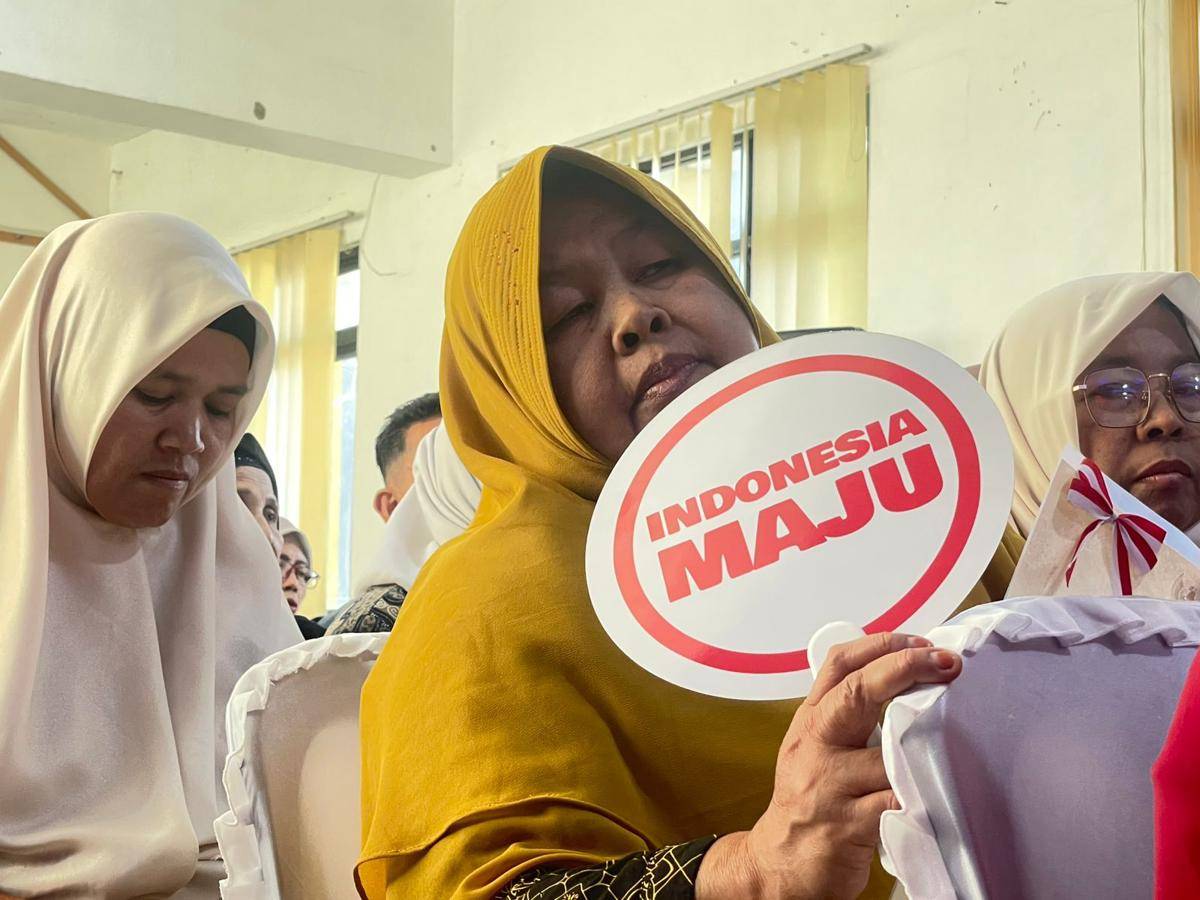 Seorang warga memegang poster Indonesia Maju saat penyerahan sertfikat tanah di Padang (Foto: IDN Times/Halbert Caniago)