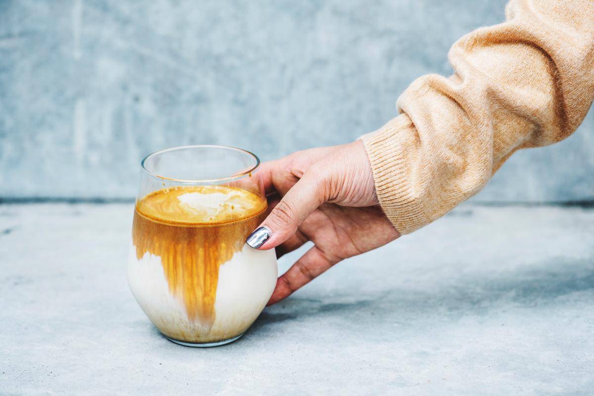 ilustrasi seseorang sedang memegang segelas dirty latte