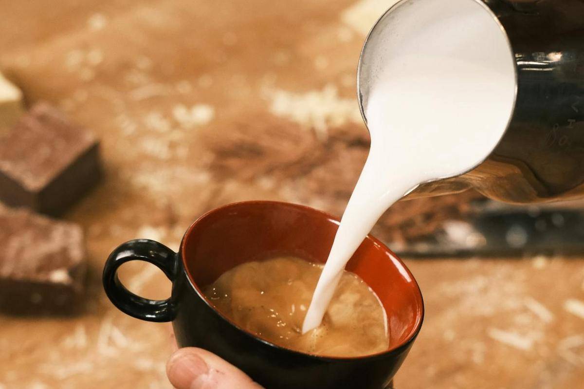 Potret menuangkan susu dalam cangkir berisi espresso