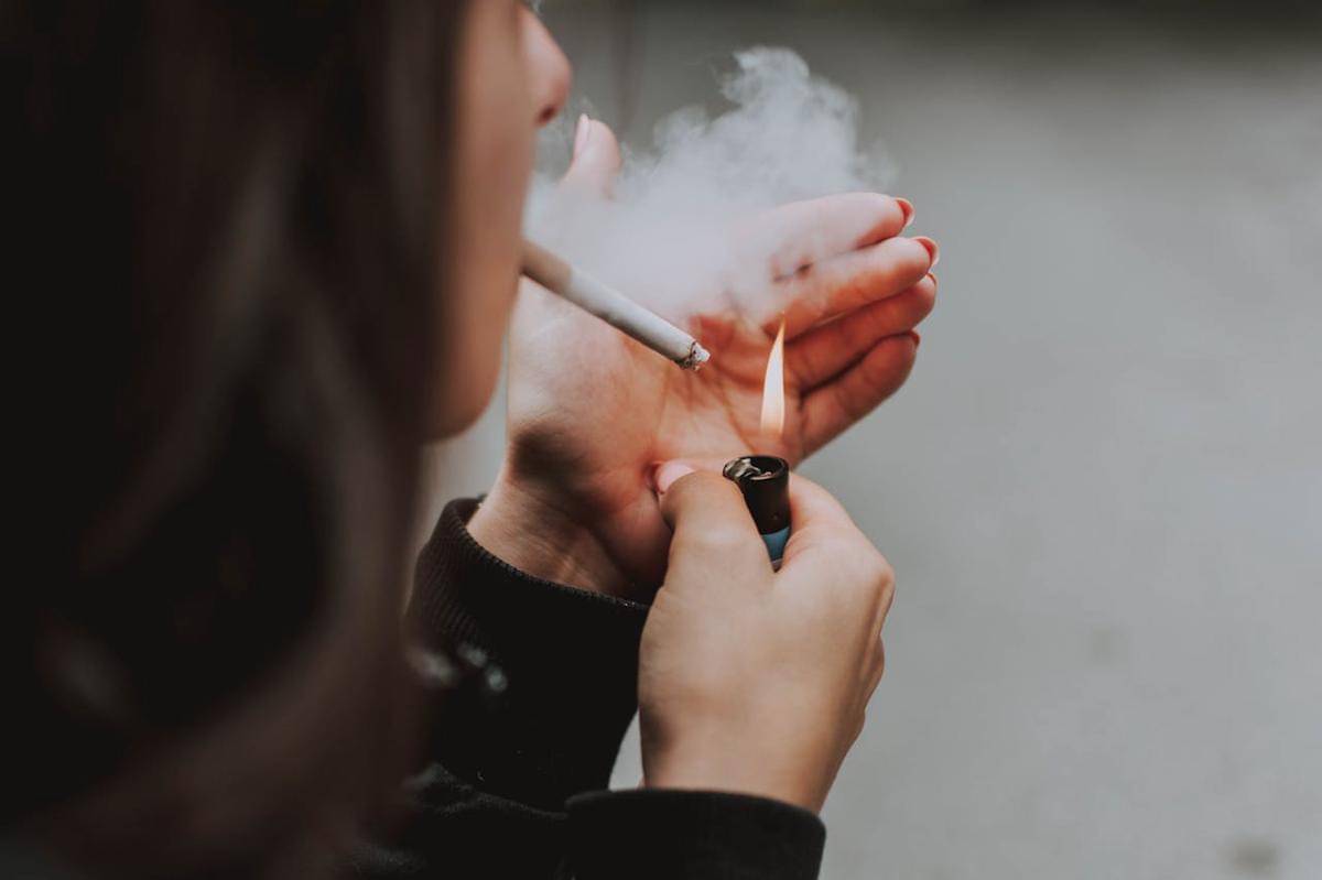 Seorang perempuan sedang membakar rokok.