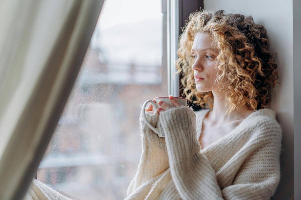 potret seseorang merenung di dekat jendela 