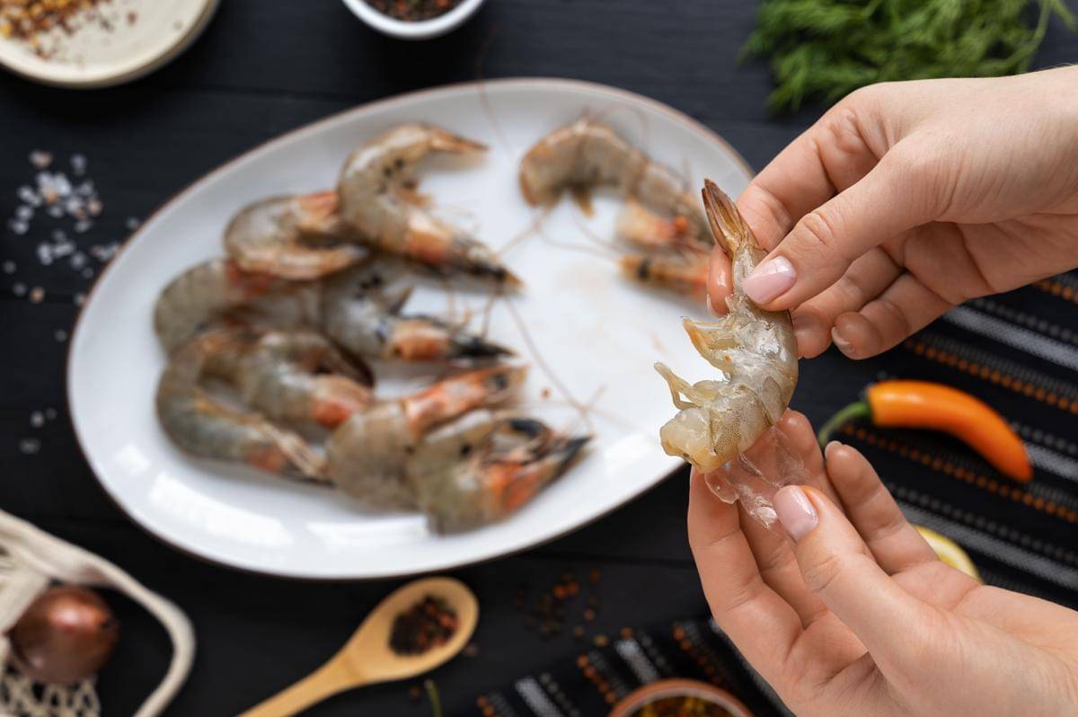 Seseorang mengupas udang dari kulitnya.