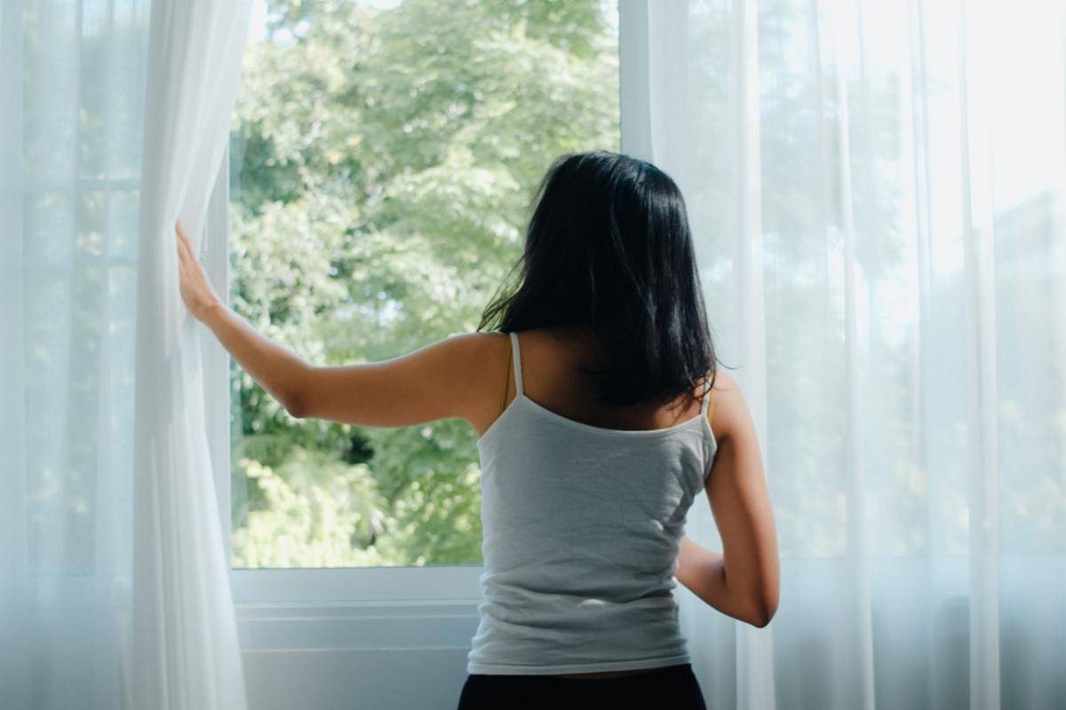 Ilustrasi perempuan membuka jendela rumahnya.