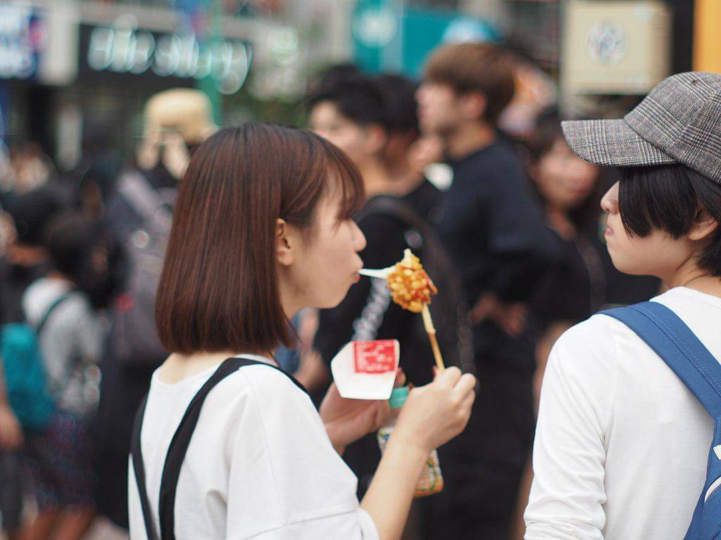 Seorang perempuan makan corndog.