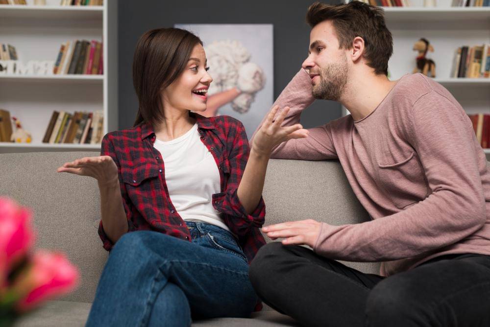 Seorang perempuan dan laki-laki sedang mengobrol di sofa.