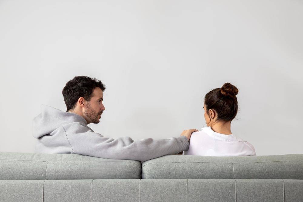 Seorang laki-laki dan perempuan duduk di sofa.