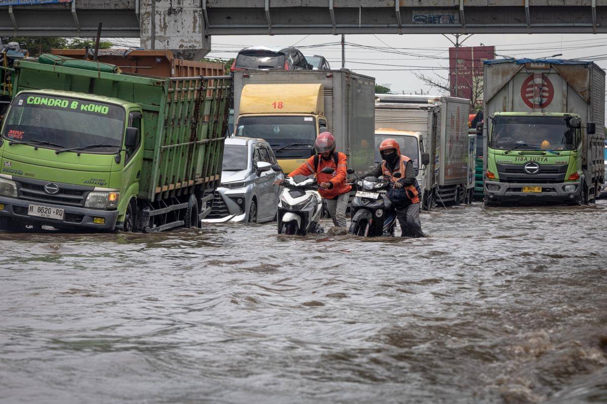 Dua warga mendorong sepeda motornya yang mogok seusai menembus genangan banjir di jalur utama pantura Semarang-Surabaya, Jalan Kaligawe Raya, Semarang, Jawa Tengah, Rabu (22/10/2025). (ANTARA FOTO/Aji Styawan)