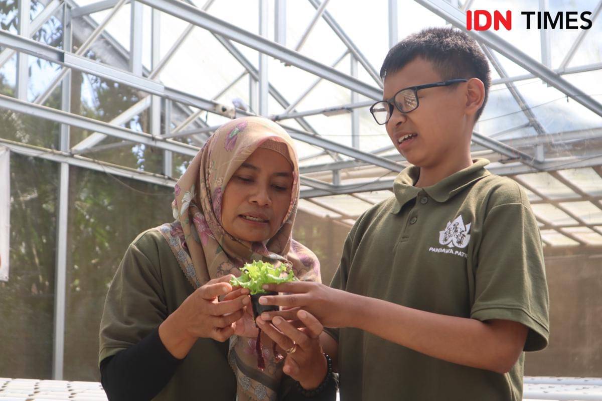 Martuti mengajarkan anaknya yang tuna netra Bagas Surpriyanto belajar mengenai tanaman selada di Green House Pandawa Patra, Boyolali. (IDN Times/Larasati Rey)