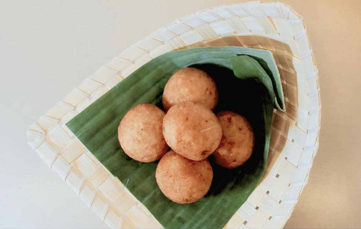 Lima buah misro berbentuk bulat berwarna keemasan tersaji di atas daun pisang dalam wadah anyaman bambu.