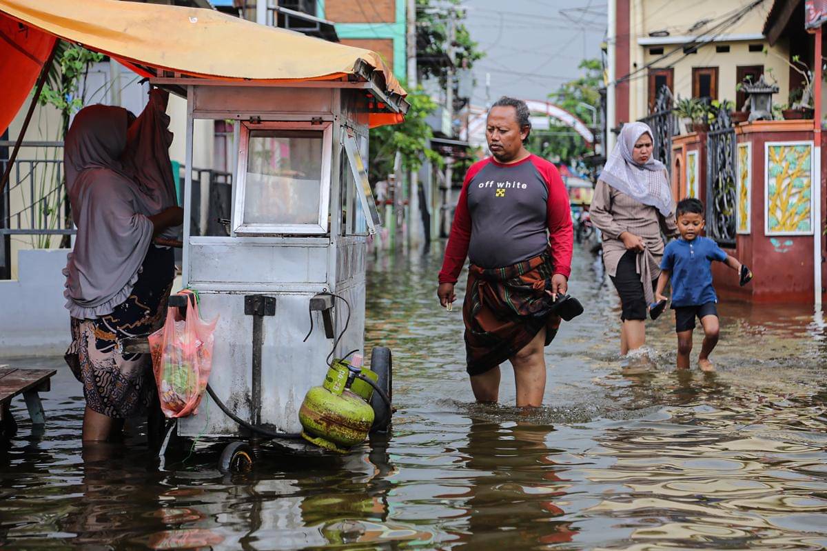 Warga berjalan di jalan yang terendam banjir di area permukiman rumahnya di Jalan Tambakrejo, Kelurahan Kaligawe, Semarang, Jawa Tengah, Sabtu (25/10/2025). (ANTARA FOTO/Makna Zaezar)