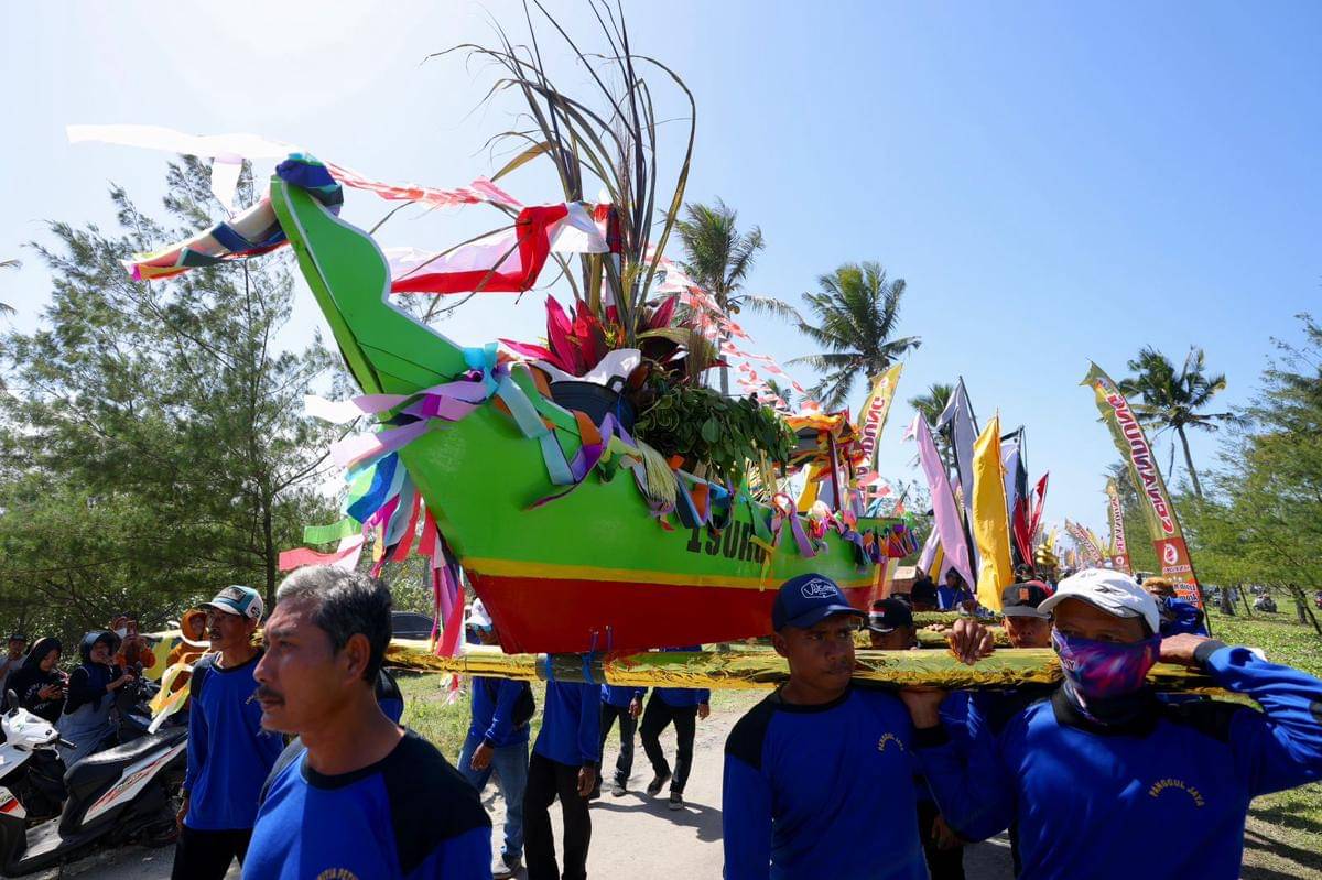 Warga menggotong perahu berhias untuk prosesi Petik Laut.