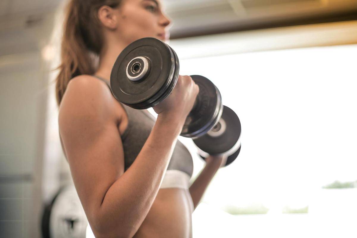 Seorang perempuan latihan beban dengan dumbbell.