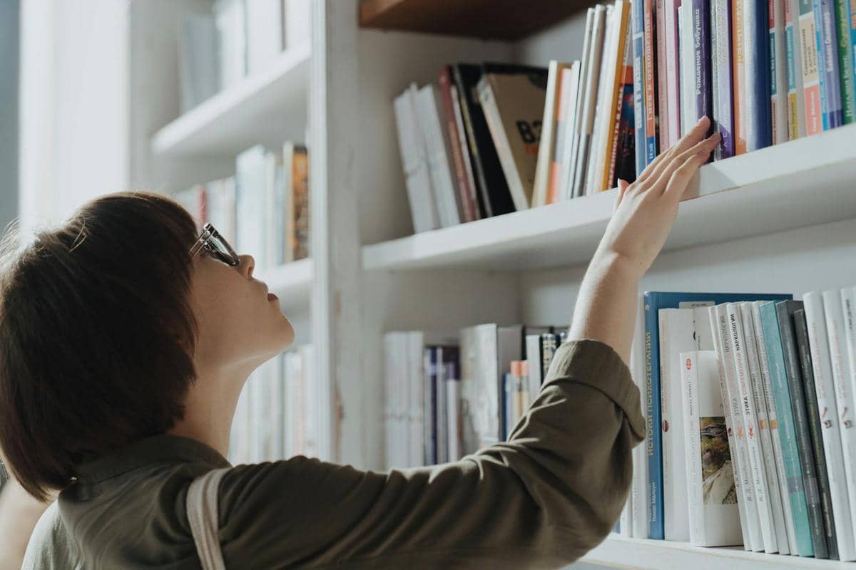 Seorang wanita memilih buku di rak.