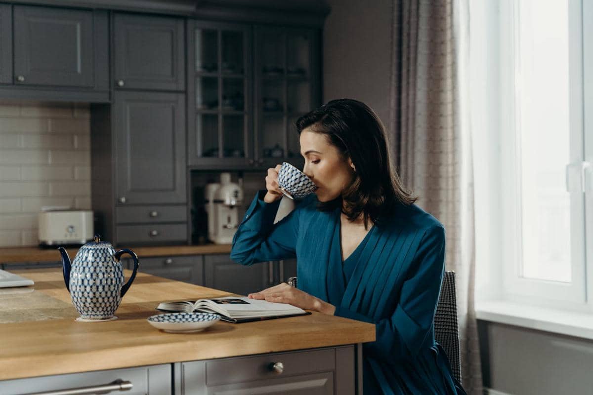Seorang perempuan menyesap teh hangat dari cangkir.