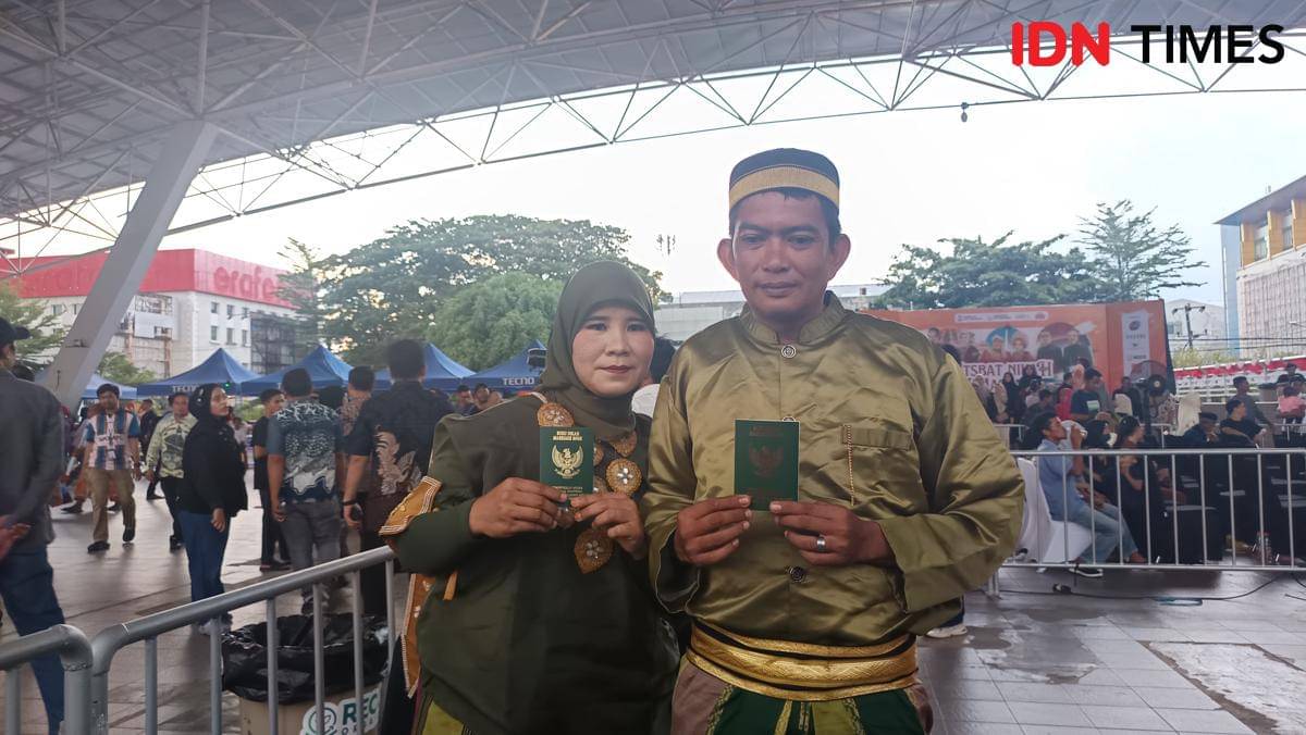 Pasangan itsbat nikah massal di Tribun Lapangan Karebosi, Jumat (7/11/2025), menunjukkan buku nikahnya. (IDN Times/Asrhawi Muin)