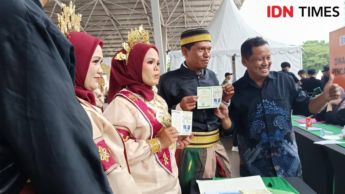 Pasangan itsbat nikah massal di Tribun Lapangan Karebosi, Jumat (7/11/2025), menunjukkan buku nikahnya. (IDN Times/Asrhawi Muin)