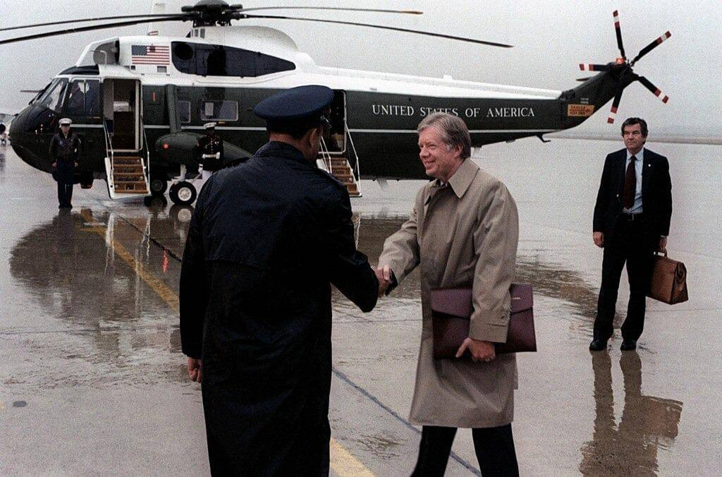  Presiden AS Jimmy Carter berjabat tangan dengan seorang perwira Angkatan Udara AS saat keberangkatannya dengan "Marine One" (helikopter Sikorsky VH-3D Sea King), di Pangkalan Angkatan Udara Andrews, Maryland (AS), pada tahun 1980.(U.S. DefenseImagery photo VIRIN: DF-SC-82-05446, Public domain, via 
