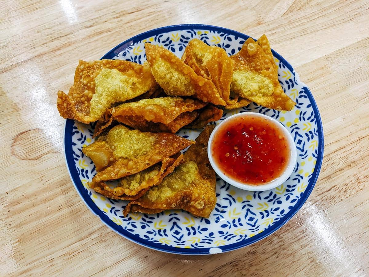 Ilustrasi pangsit goreng crispy dengan kulit bertekstur renyah dan warna keemasan sebagai sajian camilan.