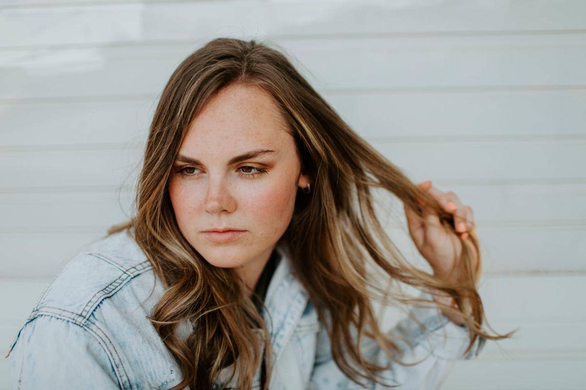 Seorang wanita sedang memegang rambutnya.