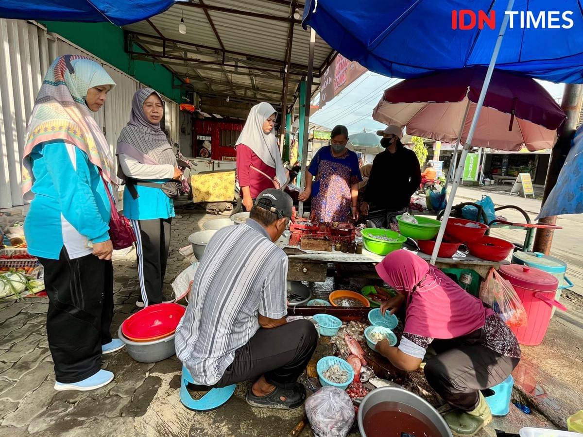 Ngatirah (kanan) menyiapkan cumi-cumi segar untuk Fiya. (IDN Times/Dhana Kencana)
