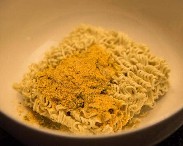Mie instan yang ditaburi bumbu.